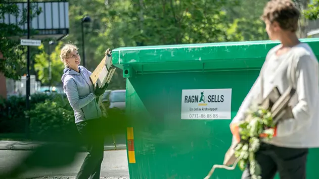 En kvinna och ung man som slänger trädgårdsavfall i en grön container