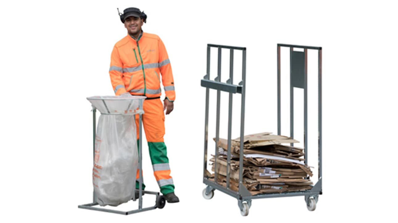 En man i orange varselkläder bredvid ett sopsäckställ och en wellpappbur