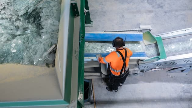 En man från Ragn-Sells fotograferad ovanifrån som står vid ett band som sorterar fönsterglas