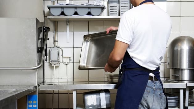 Man i restaurangkök som rengör rostfri form