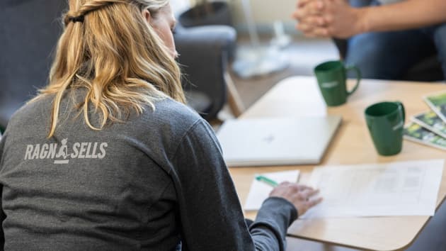 En man från Ragn-Sells i orange varselkläder går i grönska och rapsfält