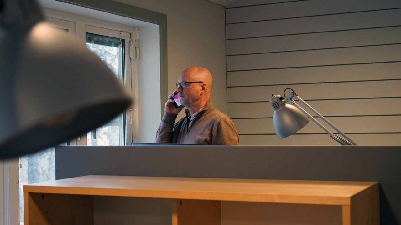 En man som st&aring;r och pratar i telefon p&aring; ett kontor