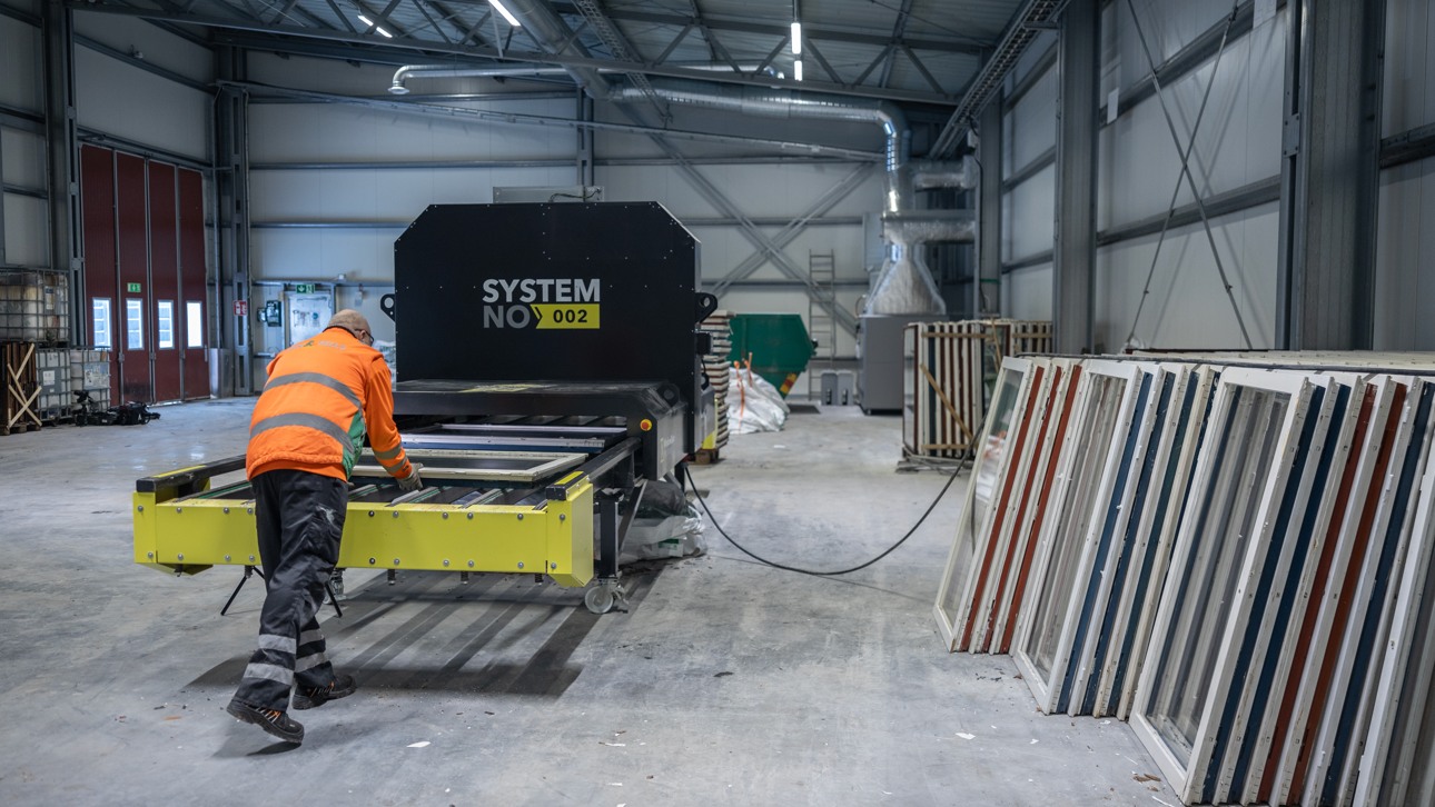 En Ragn-Sells anställd som skickar in glasrutor i en maskin för att ta bort glaset från ramen