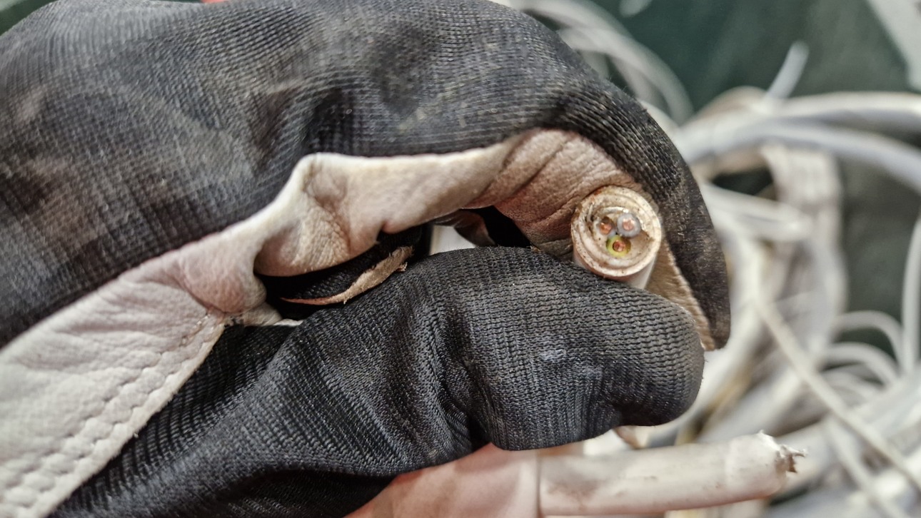En hand som h&aring;ller en kabel och visar upp inneh&aring;llet med plast och metall