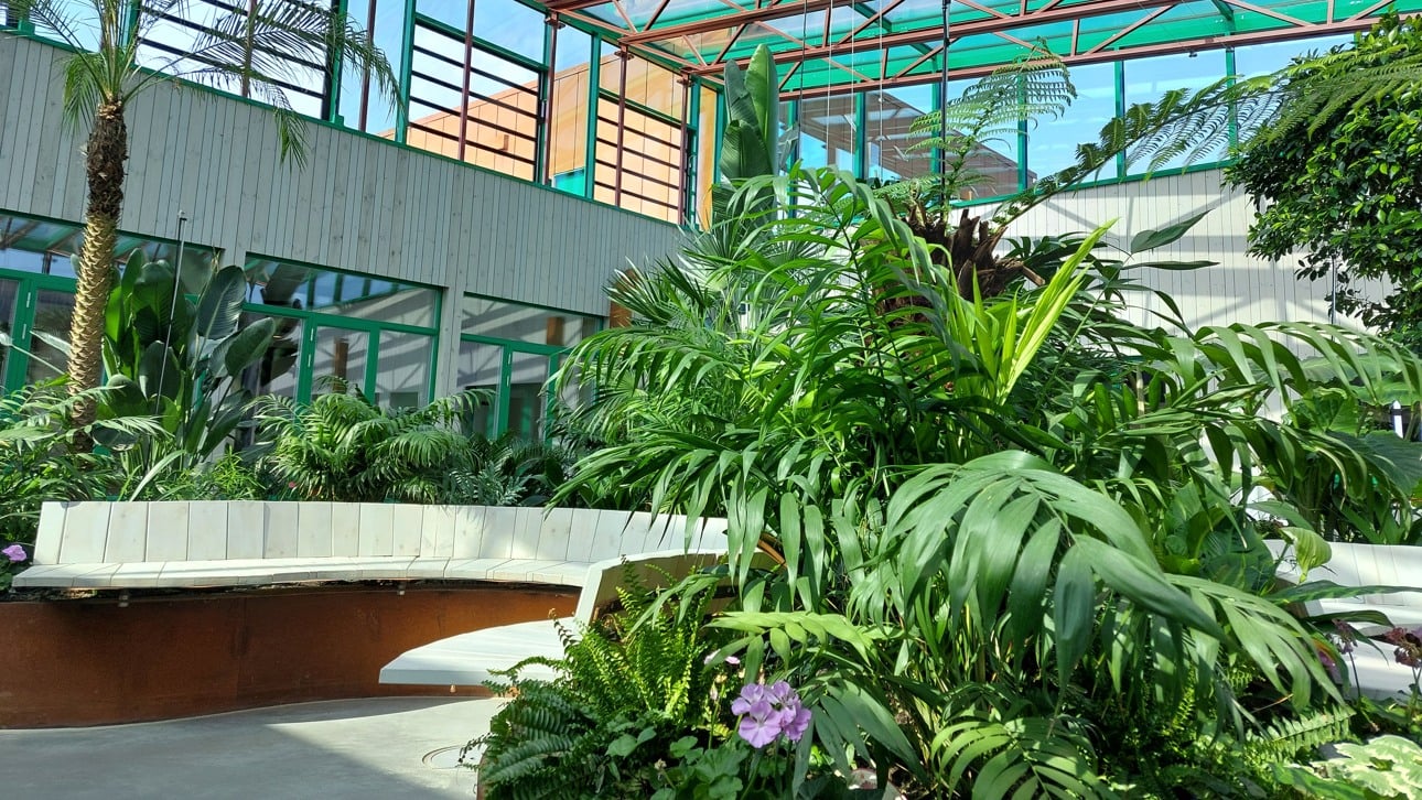 Ett stor inglasad ljusträdgård med högt i tak och fina runda sittplatser.