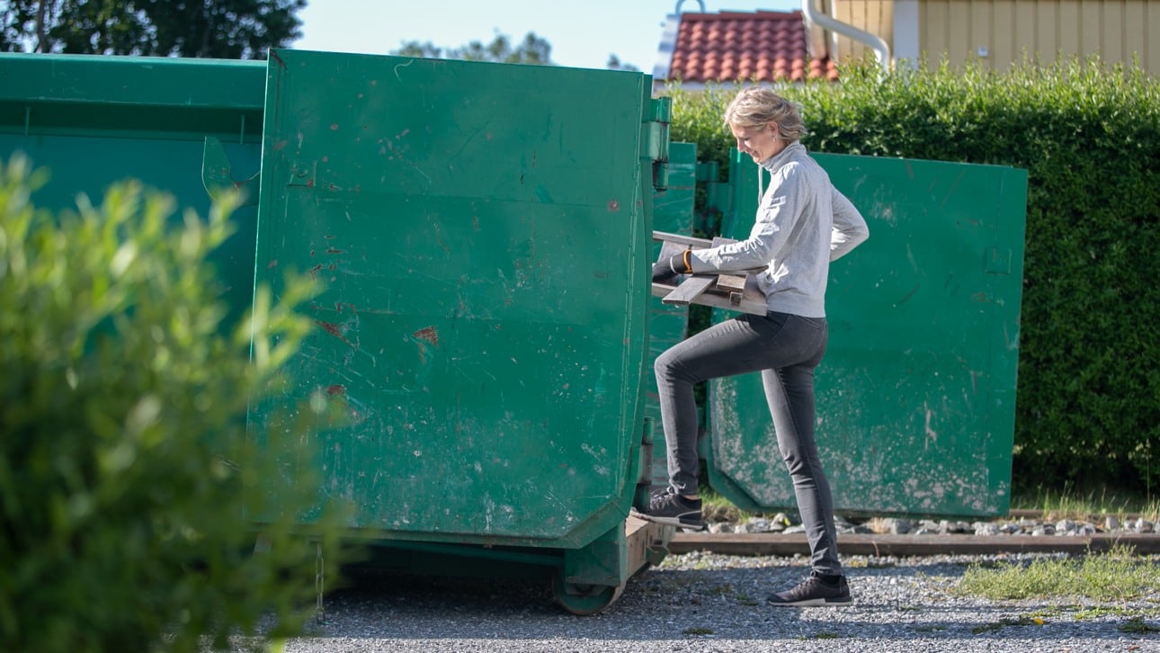 Kvinna går in i en öppen grön container från kortsidan