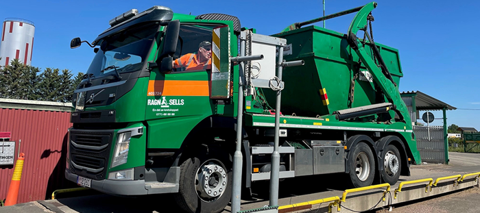 Peter Holmlind på Ragn-Sells i förarhytten på en grön lastväxlare med en container