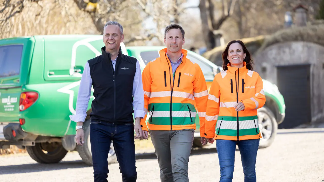 Två män och en kvinna som går på rad, två i orangea varselkläder från Ragn-Sells