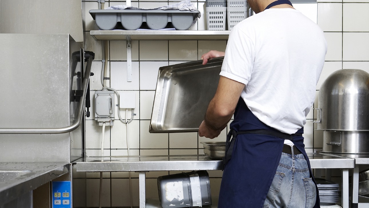 Man i restaurangkök som rengör rostfri form