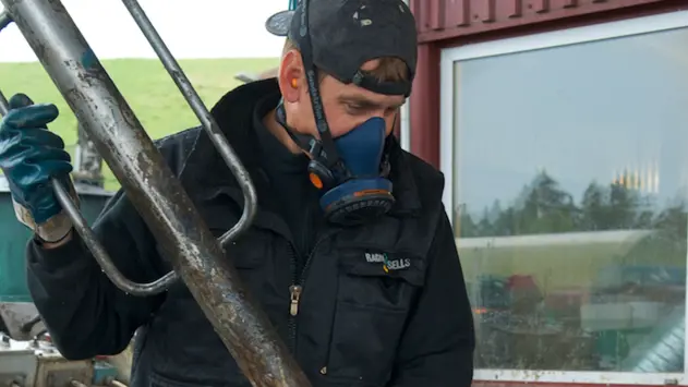 Man på Ragn-Sells som hanterar farligt avfall med mask över ansiktet