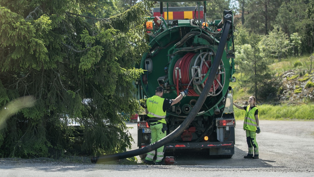 En man och kvinna från Ragn-Sells bredvid ett grönt fordon för sug- och spolning