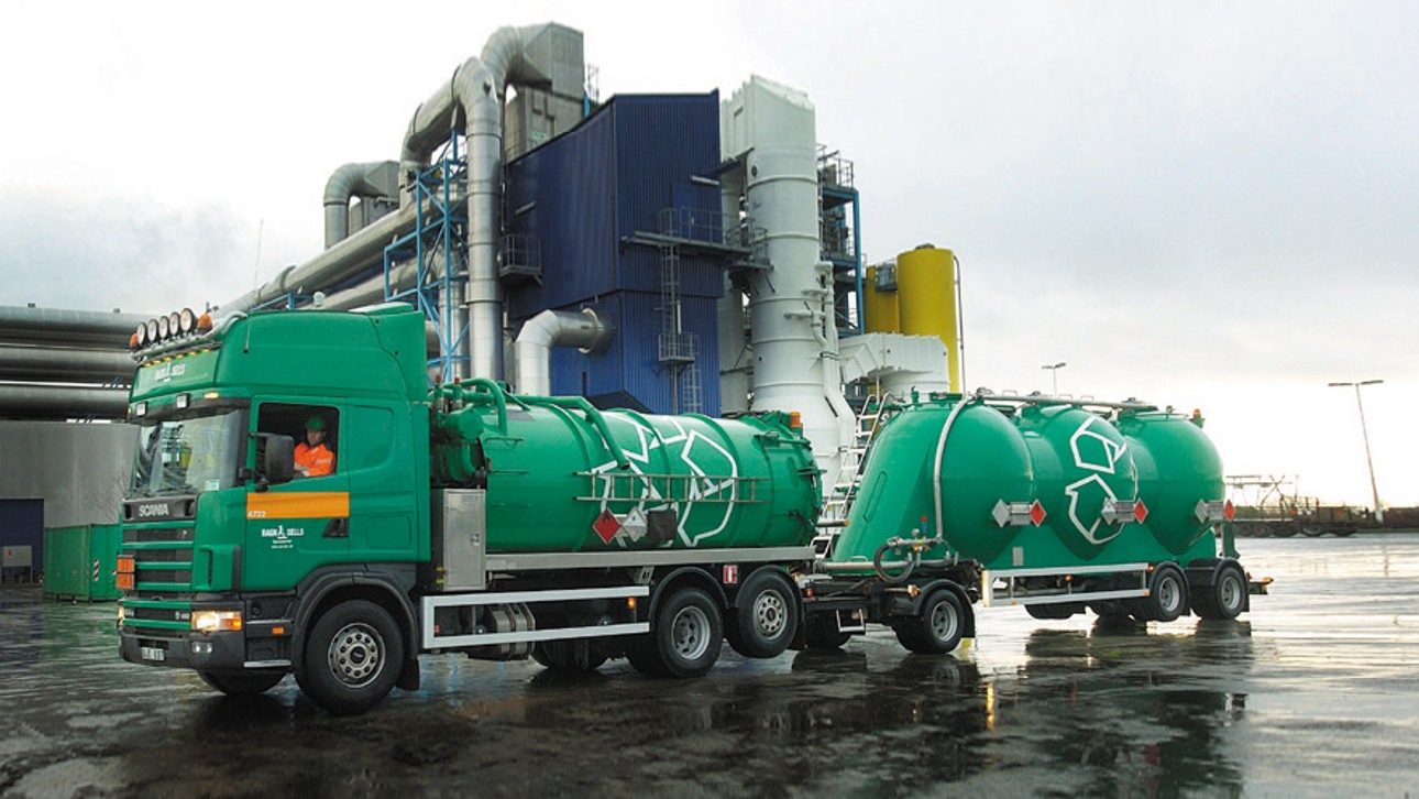 En grön Ragn-Sells slambil framför en industri