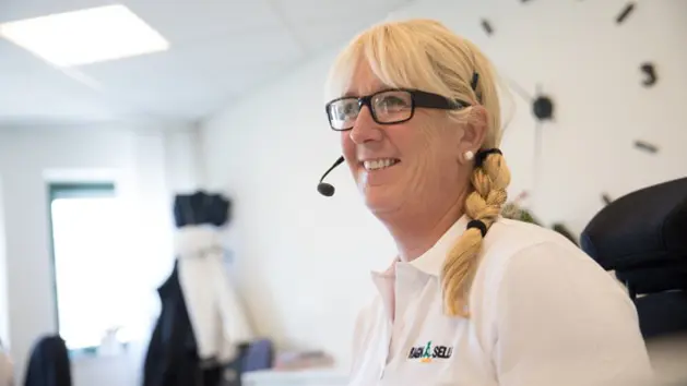 Ragn-Sells kundservice är öppen alla dagar 7-16 En kvinna med glasögon med headset och vit t-shirt med logon Ragn-Sells