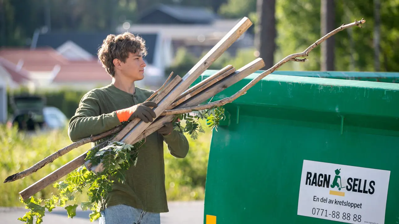 En ung man som slänger träavfall i grön container